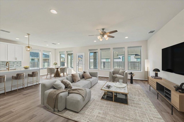 living area with light wood-style floors, visible vents, and recessed lighting