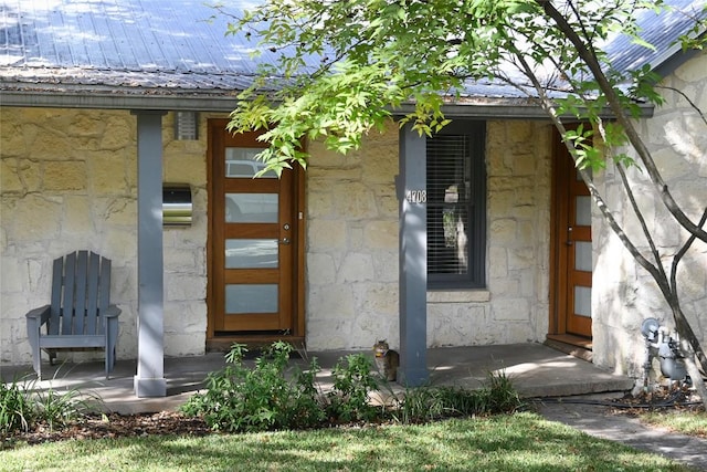 view of exterior entry featuring stone siding and metal roof