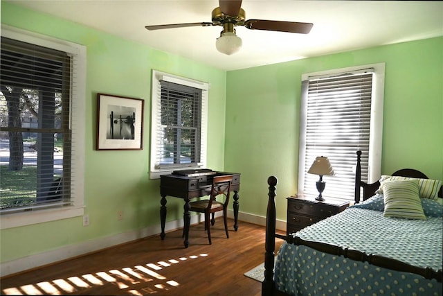 bedroom with multiple windows, wood finished floors, a ceiling fan, and baseboards