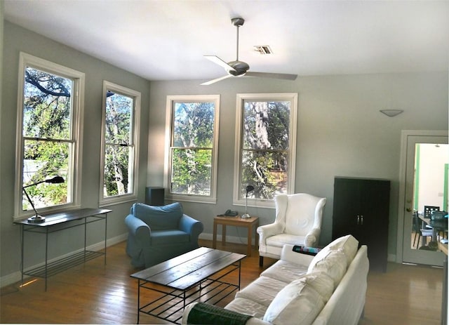 living area featuring a wealth of natural light, visible vents, and wood finished floors