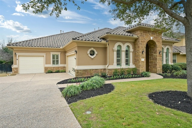 mediterranean / spanish home featuring an attached garage, stone siding, driveway, stucco siding, and a front lawn