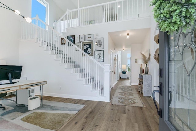 entrance foyer with stairway, a high ceiling, baseboards, and wood finished floors