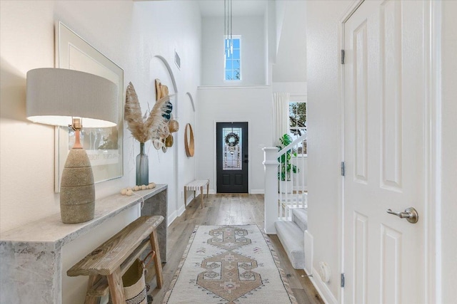 foyer featuring a towering ceiling, light wood-style floors, baseboards, and visible vents