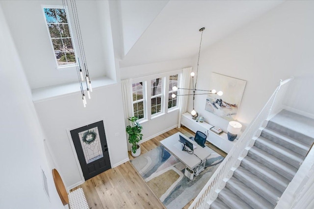 entryway with a chandelier, vaulted ceiling, stairway, and wood finished floors