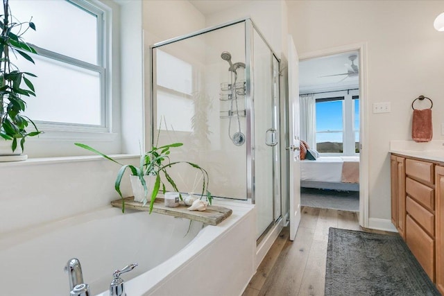 ensuite bathroom featuring a healthy amount of sunlight, a shower stall, and hardwood / wood-style floors