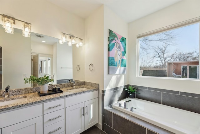 full bathroom featuring a garden tub, double vanity, a sink, and visible vents