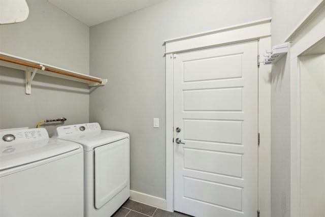 laundry area with baseboards, laundry area, dark tile patterned floors, and washer and dryer