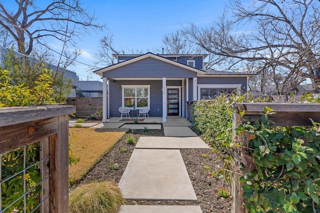 bungalow-style home with covered porch and fence