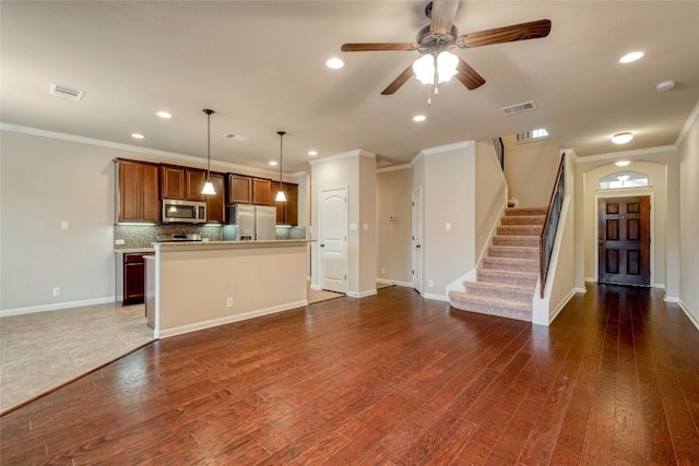 unfurnished living room featuring wood finished floors, visible vents, and crown molding