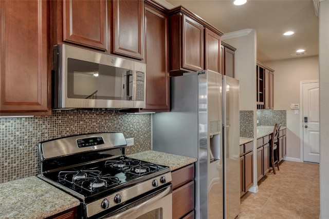 kitchen with light stone countertops, tasteful backsplash, light tile patterned floors, and stainless steel appliances