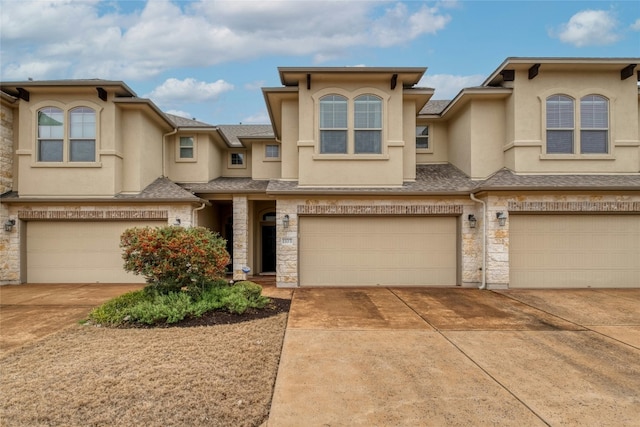 townhome / multi-family property featuring a shingled roof, concrete driveway, stone siding, an attached garage, and stucco siding