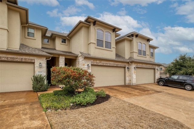 townhome / multi-family property featuring stone siding, driveway, an attached garage, and stucco siding