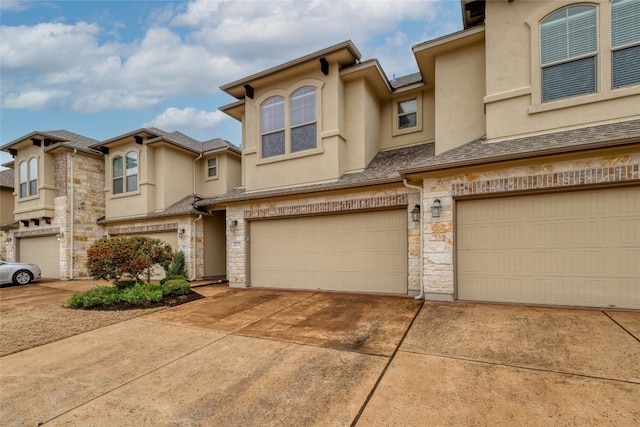 townhome / multi-family property featuring a garage, stone siding, driveway, and stucco siding