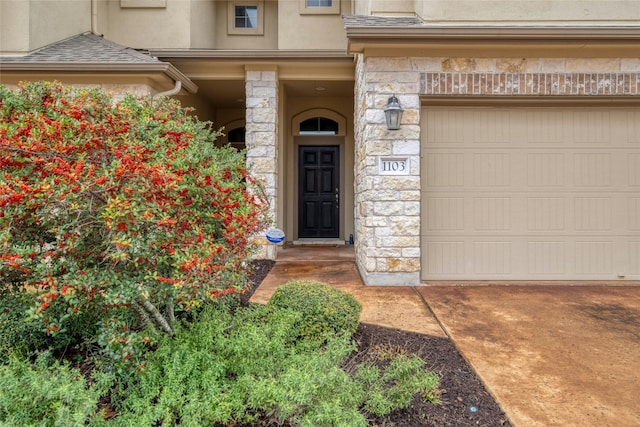 property entrance featuring a garage, stone siding, a shingled roof, and stucco siding