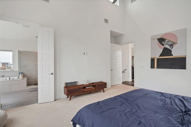 carpeted bedroom featuring visible vents, a towering ceiling, and ensuite bathroom