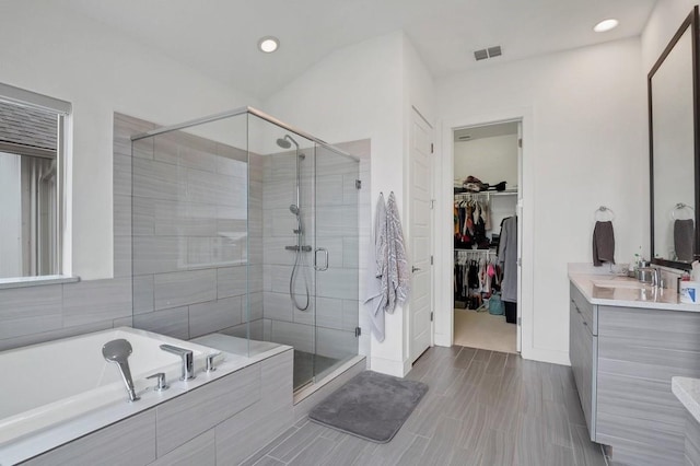 full bathroom featuring a garden tub, vanity, visible vents, a spacious closet, and a stall shower