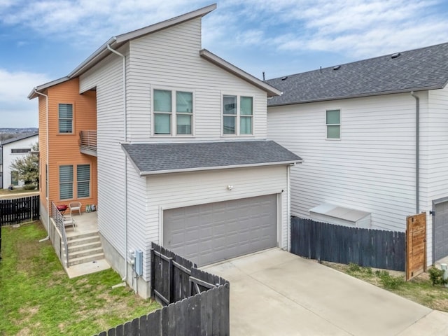 view of side of home with a garage, concrete driveway, roof with shingles, and fence