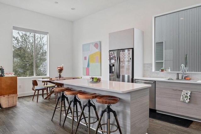 kitchen featuring dark wood-type flooring, a sink, light countertops, appliances with stainless steel finishes, and modern cabinets