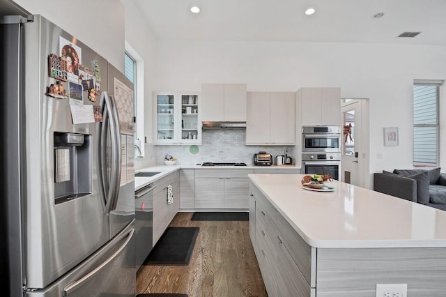 kitchen featuring stainless steel appliances, dark wood-style flooring, a sink, light countertops, and backsplash