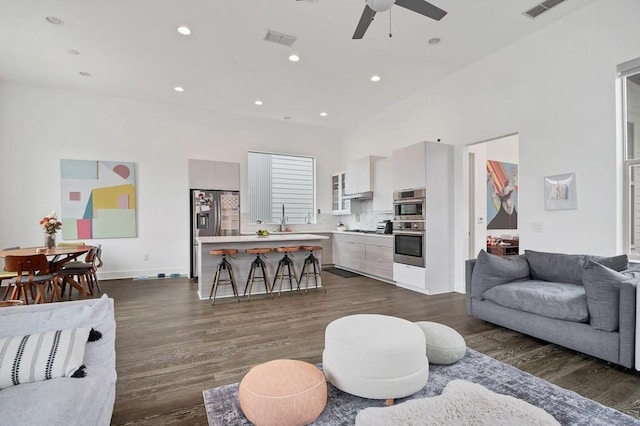 living area with recessed lighting, dark wood-style flooring, and visible vents