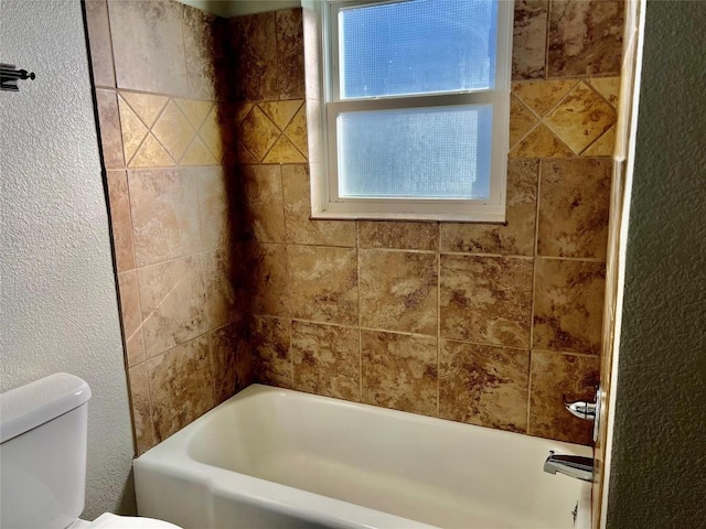 bathroom featuring shower / bathtub combination, a textured wall, and toilet