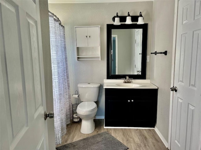 bathroom featuring toilet, wood finished floors, vanity, and baseboards