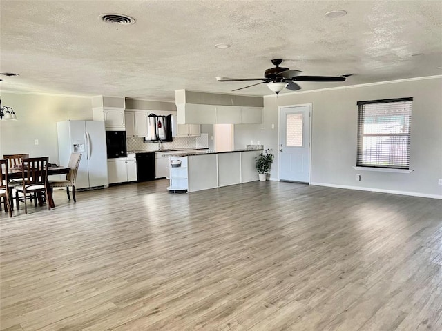 living area with light wood-style flooring, visible vents, ceiling fan, and baseboards