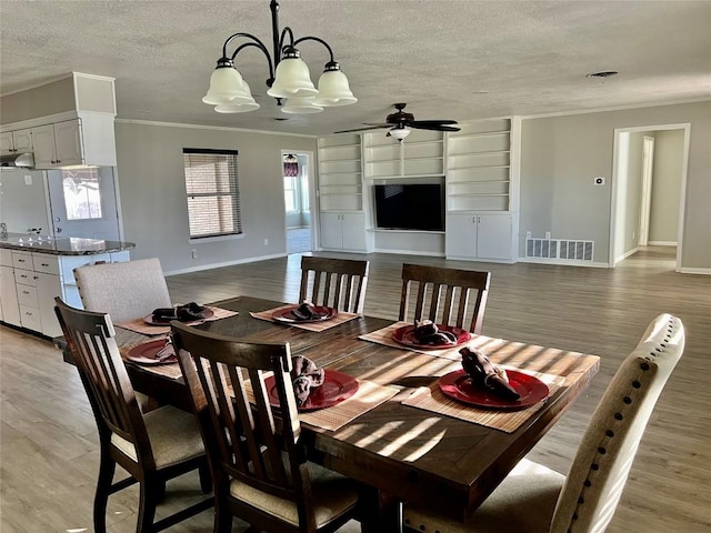 dining space featuring crown molding, visible vents, a textured ceiling, light wood-type flooring, and baseboards