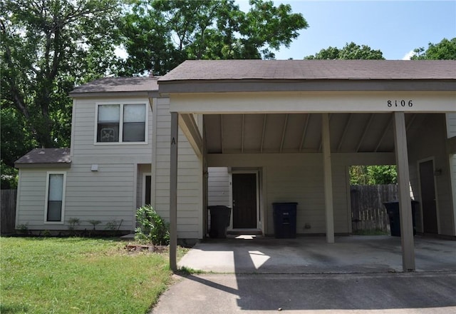 view of front of property featuring board and batten siding, an attached carport, a front lawn, and fence