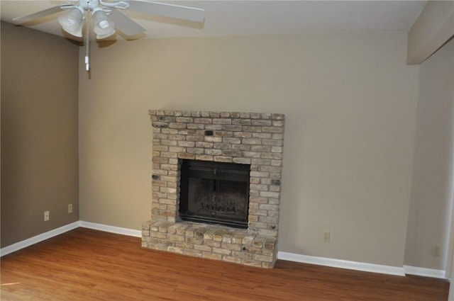 unfurnished living room with a brick fireplace, a ceiling fan, baseboards, and wood finished floors