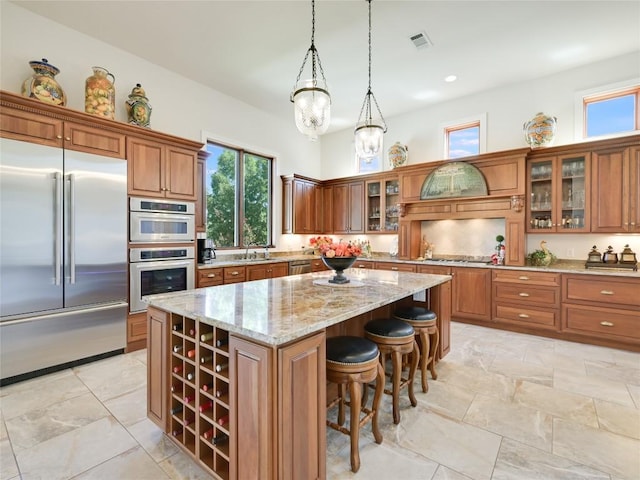 kitchen featuring brown cabinets, a kitchen island, light stone counters, and stainless steel appliances