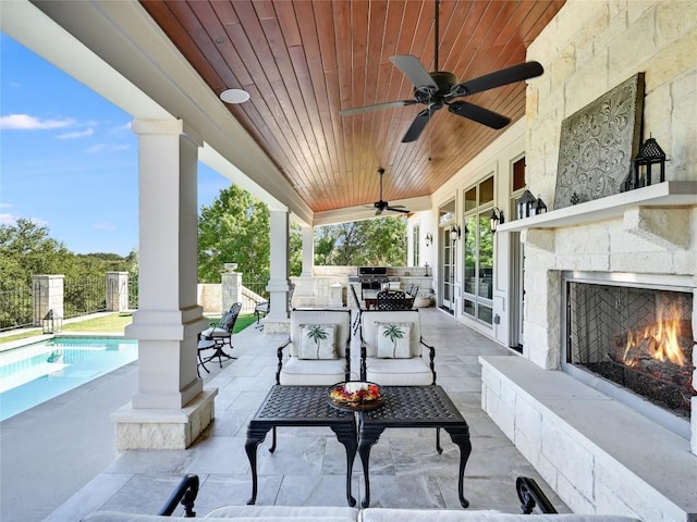 view of patio / terrace featuring an outdoor living space with a fireplace, a fenced in pool, a ceiling fan, and area for grilling