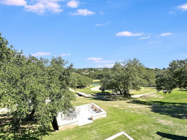 view of property's community featuring view of golf course and a yard