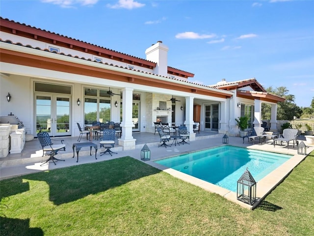 rear view of property featuring french doors, a fenced in pool, a patio area, ceiling fan, and a yard