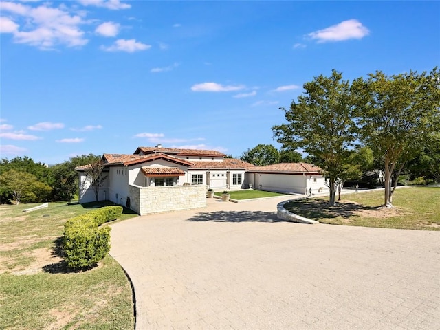 mediterranean / spanish-style home featuring a tile roof, stucco siding, a garage, driveway, and a front lawn