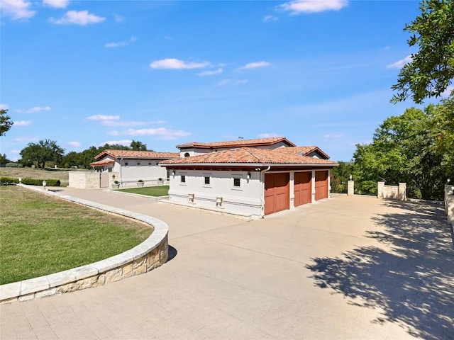 view of front of house featuring a tile roof, concrete driveway, a front lawn, fence, and a garage
