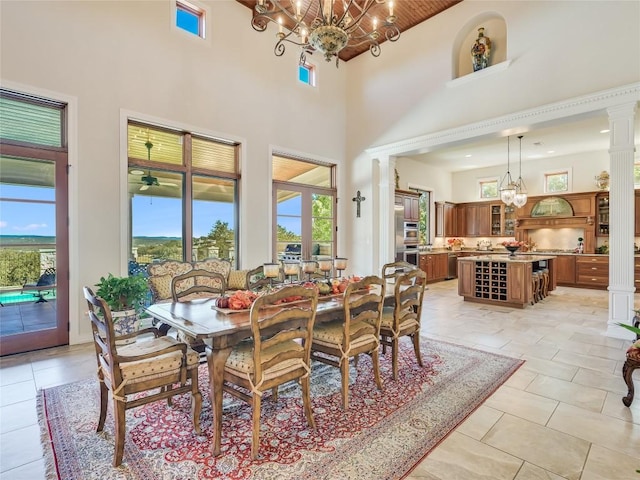 dining room with a healthy amount of sunlight, a towering ceiling, a notable chandelier, and decorative columns