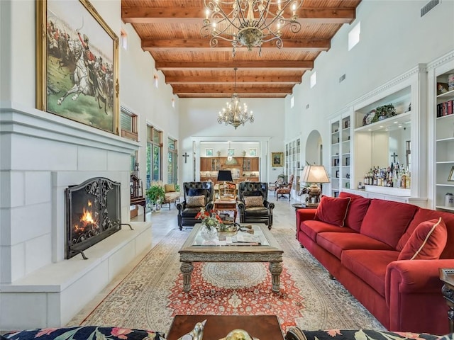 living room featuring wood ceiling, a towering ceiling, beamed ceiling, a tiled fireplace, and a notable chandelier