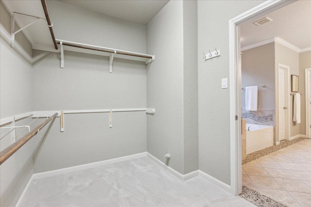 spacious closet with light carpet, light tile patterned floors, and visible vents