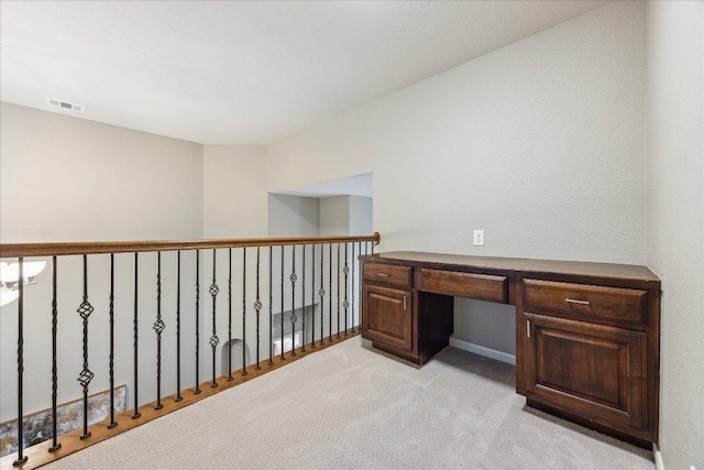 unfurnished office featuring built in desk, visible vents, and light carpet