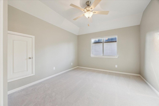 spare room with a ceiling fan, light colored carpet, vaulted ceiling, and baseboards