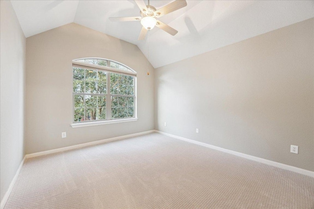 empty room with lofted ceiling, ceiling fan, carpet flooring, and baseboards