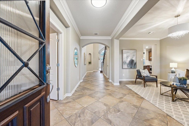 entryway with baseboards, visible vents, arched walkways, a textured ceiling, and crown molding