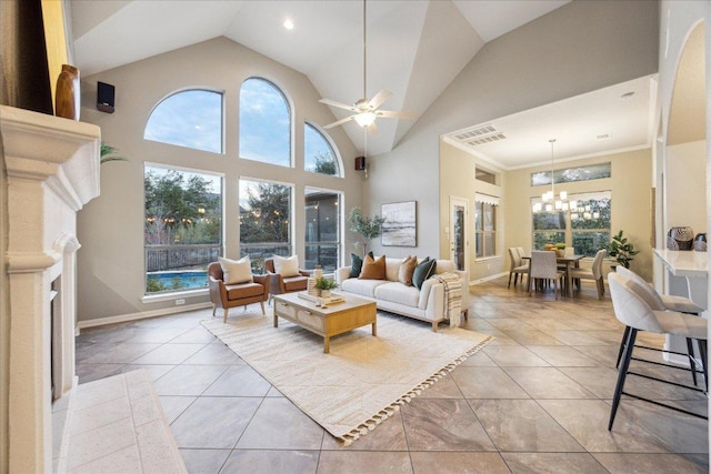 living area featuring ceiling fan with notable chandelier, high vaulted ceiling, visible vents, and a wealth of natural light