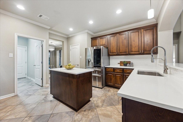 kitchen with stainless steel fridge, visible vents, a kitchen island, light countertops, and a sink