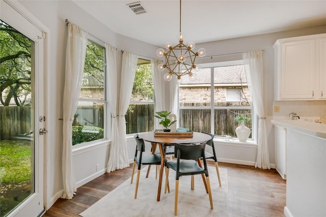 dining area with an inviting chandelier, baseboards, visible vents, and wood finished floors