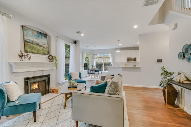 living area featuring light wood finished floors, baseboards, visible vents, a fireplace, and recessed lighting