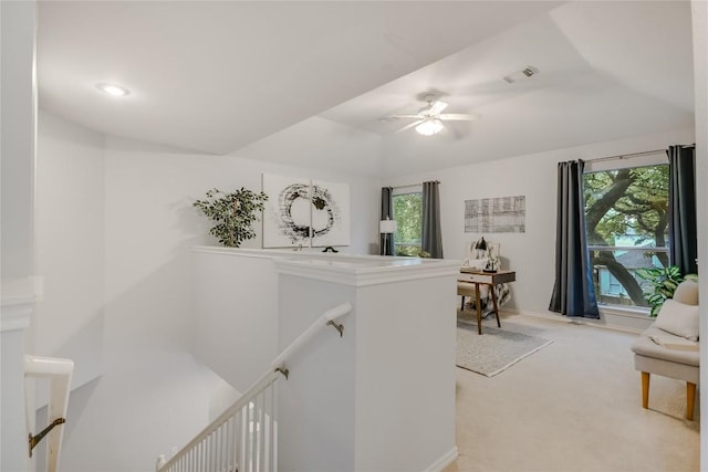 hallway with vaulted ceiling, visible vents, light colored carpet, and an upstairs landing