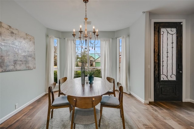 dining area with a chandelier, wood finished floors, and baseboards