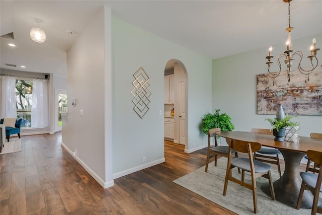 dining area featuring dark wood-style floors, arched walkways, baseboards, and an inviting chandelier